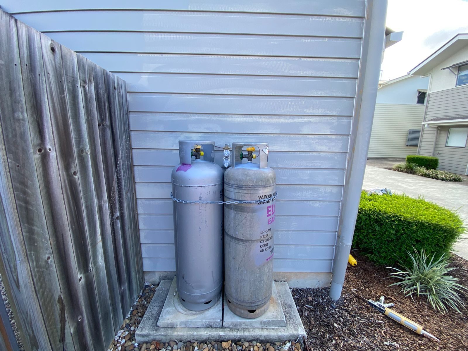 Before: weathered exterior cladding beside gas bottles, South Brisbane