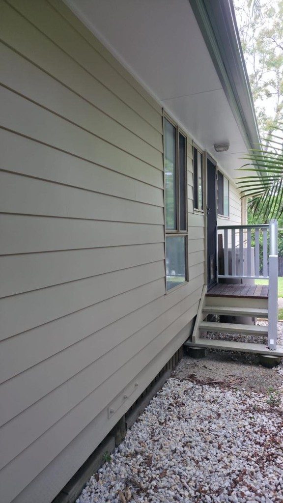 Sage green weatherboard house exterior with white stairs and dark trim